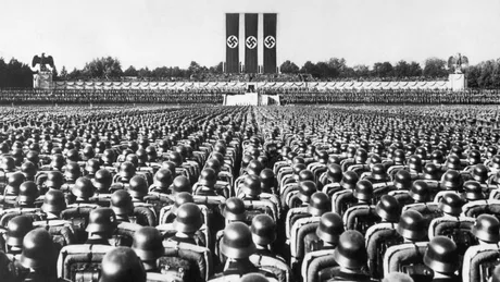 O adunare masivă cu soldați și simboluri naziste în fundal.