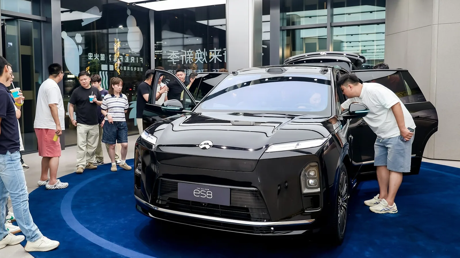 Oameni admirând un vehicul electric într-un showroom din China.