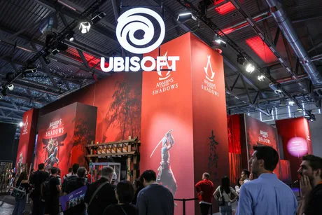Stand Ubisoft la un eveniment, cu oameni admirând produsele și grafica.