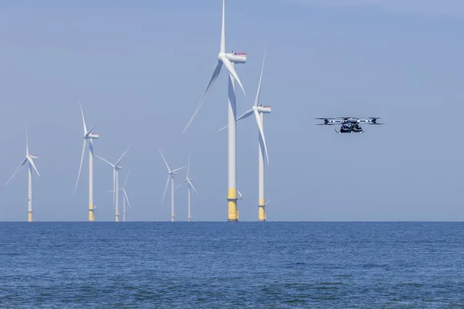 Turbine eoliene pe fundalul mării, cu un dronă în zbor.