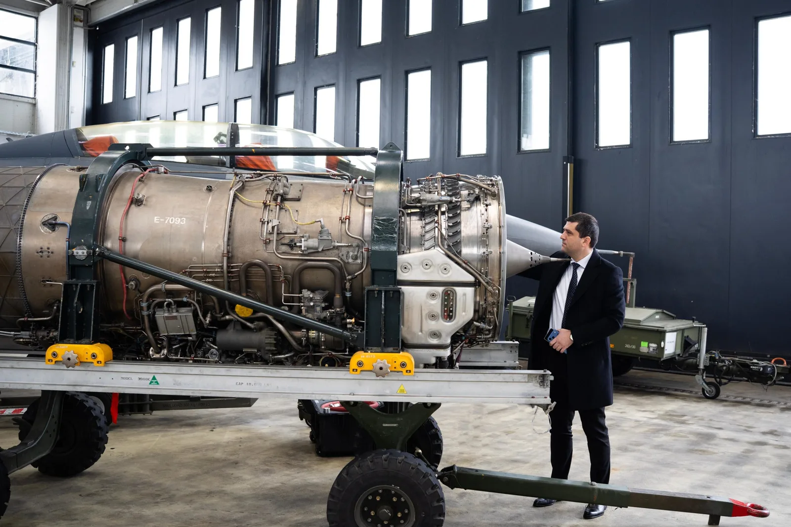 Un bărbat inspectează un motor de avion într-un atelier tehnic.