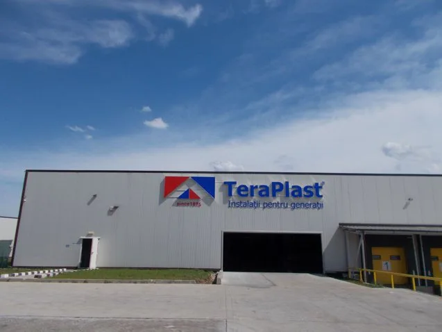 Clădirea TeraPlast cu sigla companiei pe fațadă, sub un cer senin.