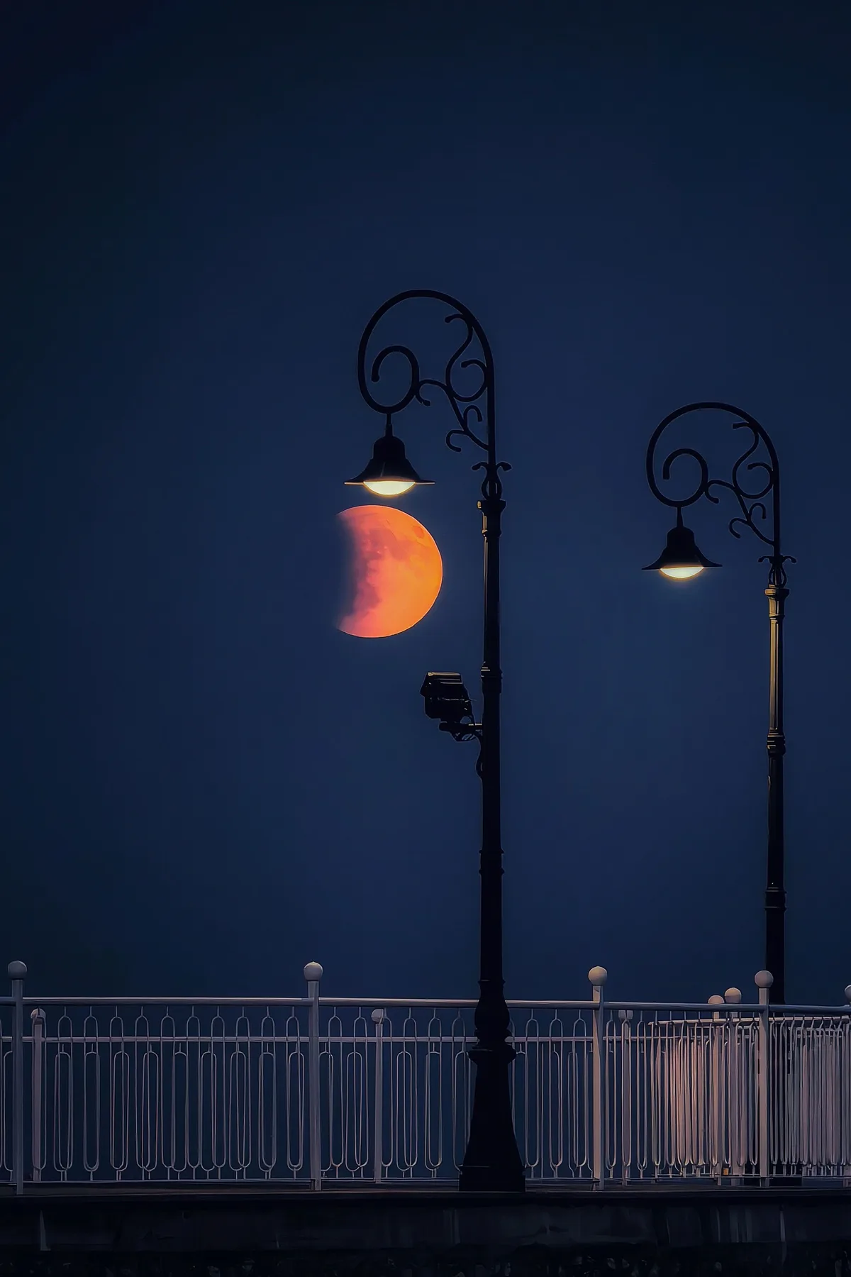 Luminile stradale reflectate în luna plină pe fundalul nopții.