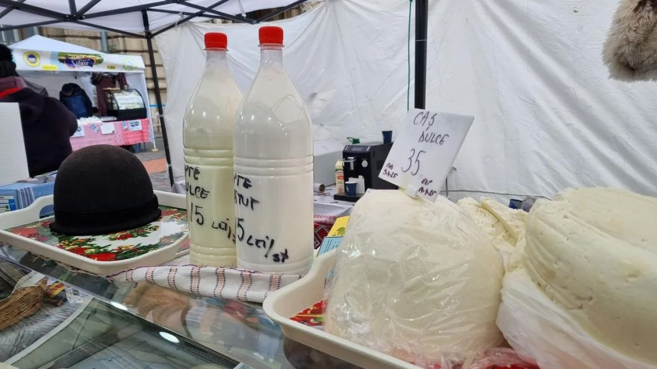 Produse lactate expuse la o tarabă, cu sticle de lapte și brânză.