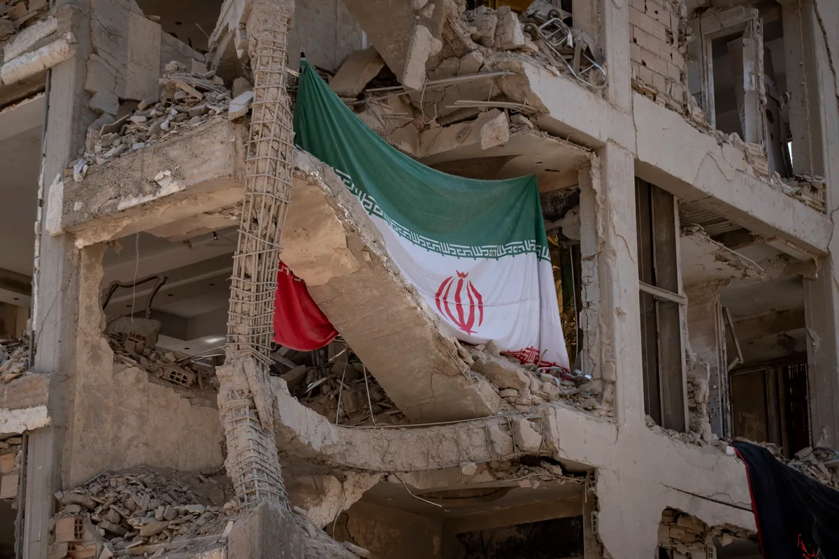 Clădire distrusă cu steagul Iranului expus în ruine.