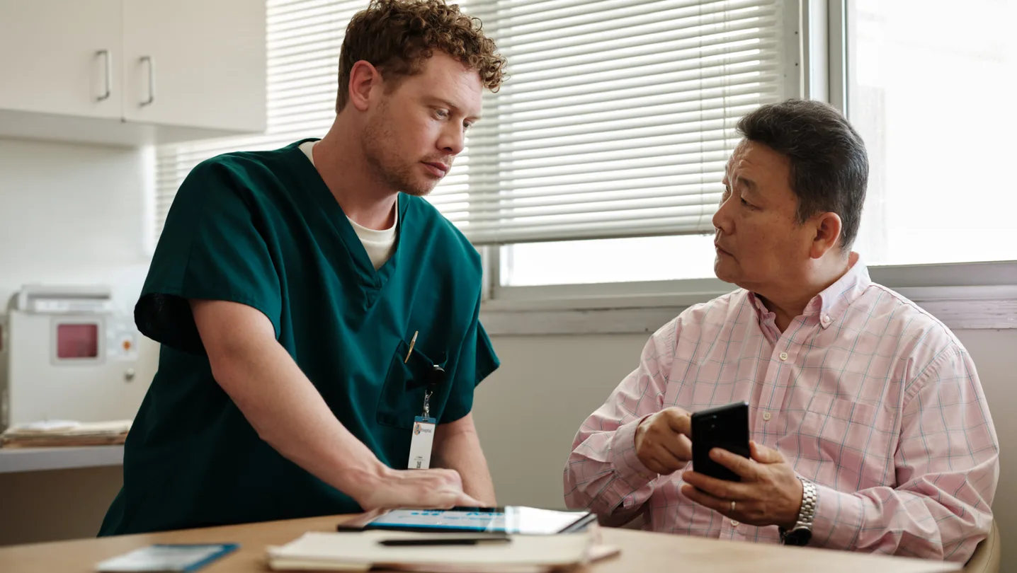 Un lucrător din sănătate discută cu un pacient despre utilizarea tehnologiei.
