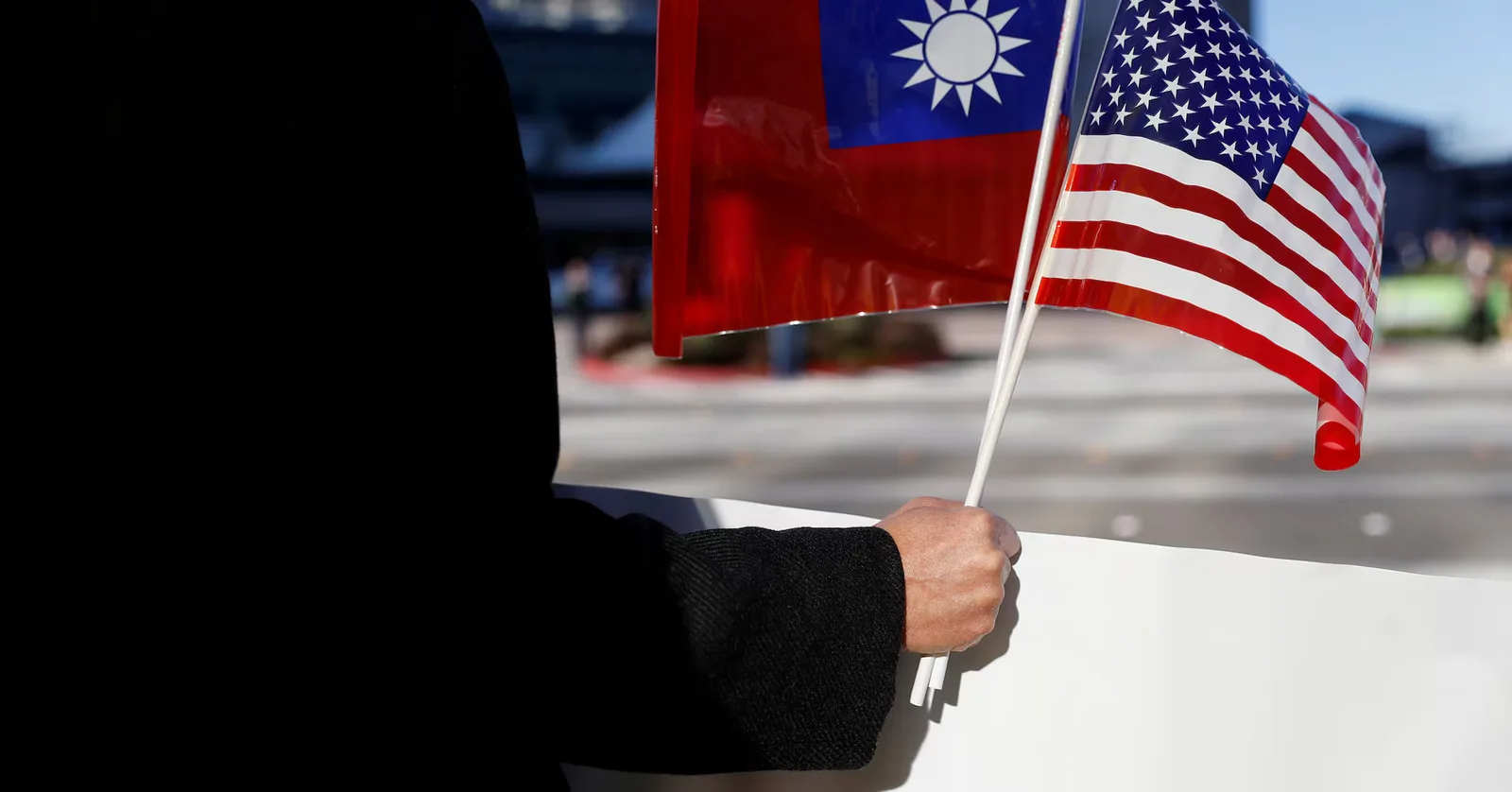 Un bărbat ține steagurile Taiwanului și SUA, simbolizând relațiile internaționale.