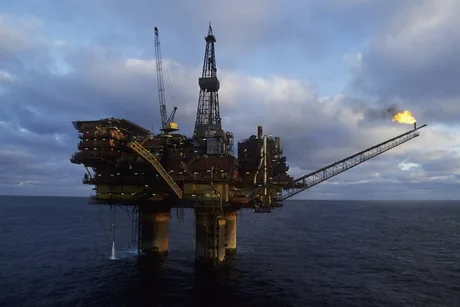 Platformă de extracție petrolieră în mare, cu flacără vizibilă.