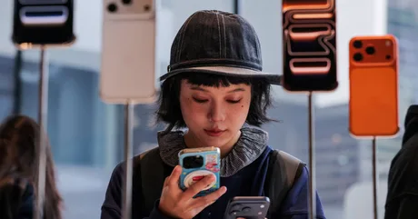 O tânără examinează telefoanele iPhone într-un magazin Apple.