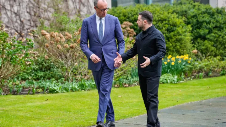 Zelenski discută cu un oficial pe un teren verde, în contextul negocierilor internaționale.