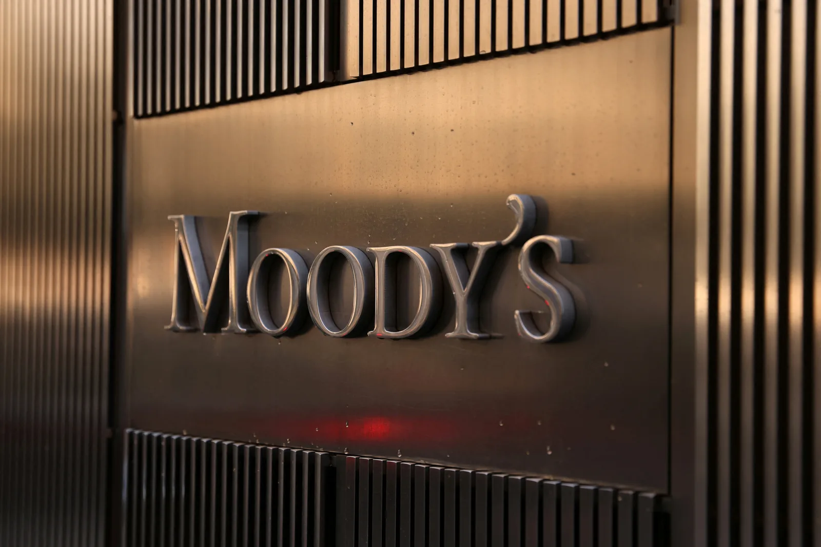 Logo-ul Moody's pe un fundal metalic, simbolizând evaluarea financiară.