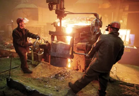 Doi muncitori în acțiune la o fabrică de prelucrare a metalelor.