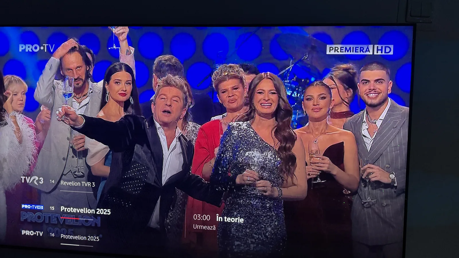 Oameni pe scenă, celebrând un eveniment televizat, cu muzică și distracție.