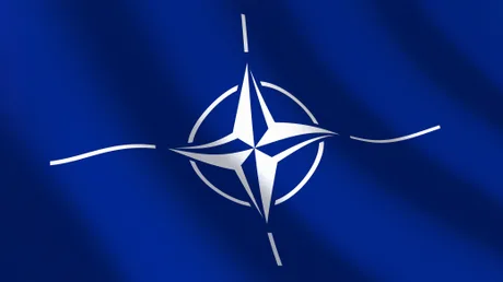 Steagul NATO fluturând, simbol al alianței și securității transatlantice.