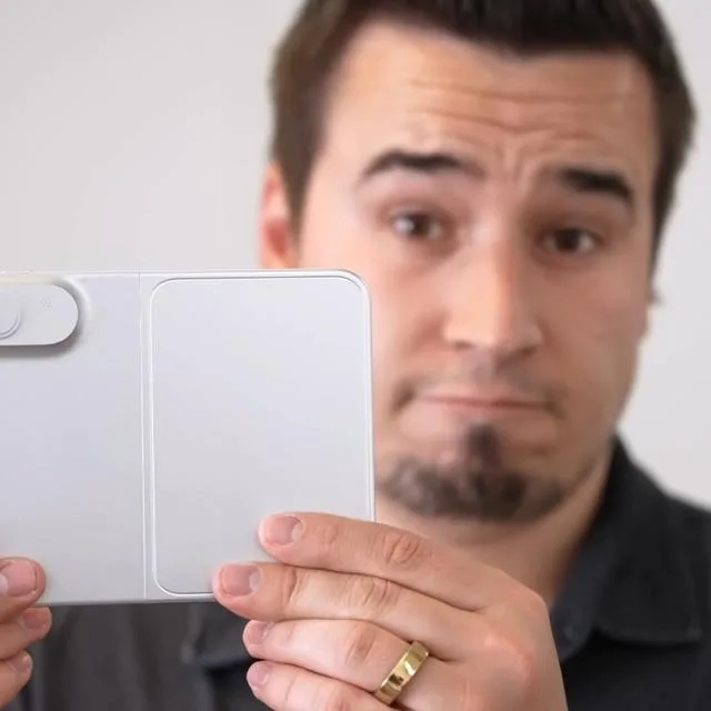 Un bărbat ține o machetă a unui telefon pliabil, arătând detalii interesante.