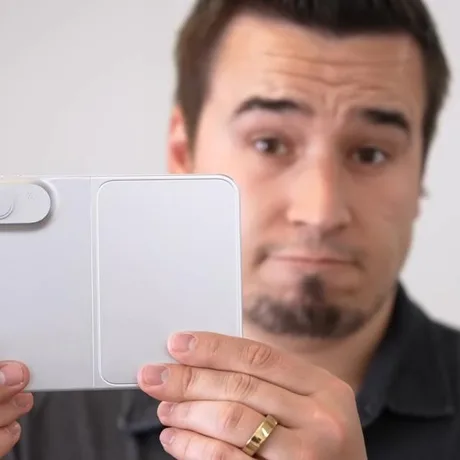 Un bărbat ține o machetă a unui telefon pliabil, arătând detalii interesante.