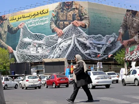 O femeie trece pe lângă un mural cu soldați în Teheran.
