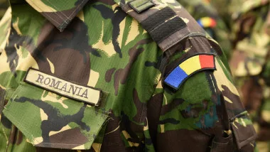 Uniformă militară românească cu insigna națională pe umăr.