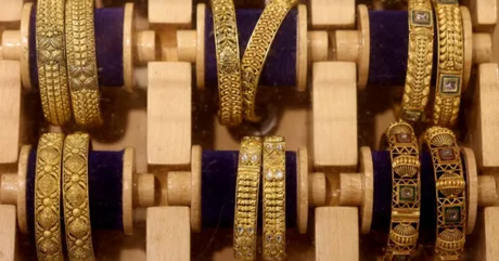 Bijuterii din aur expuse pe suporturi din lemn, reflectând lumina.