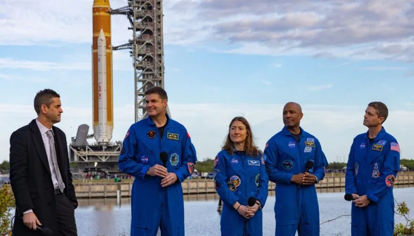 Cei patru astronauți pregătiți pentru misiunea Artemis 2 în fața rachetei.