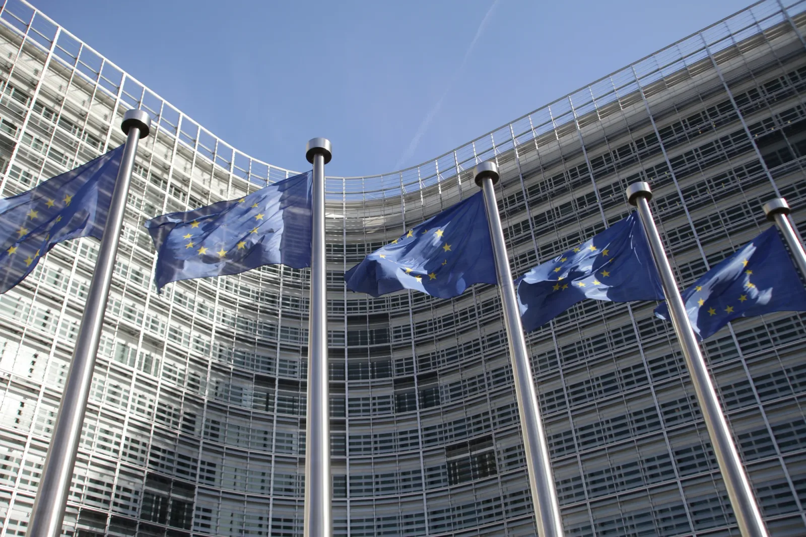 Clădirea Comisiei Europene cu steaguri fluturând în vânt.