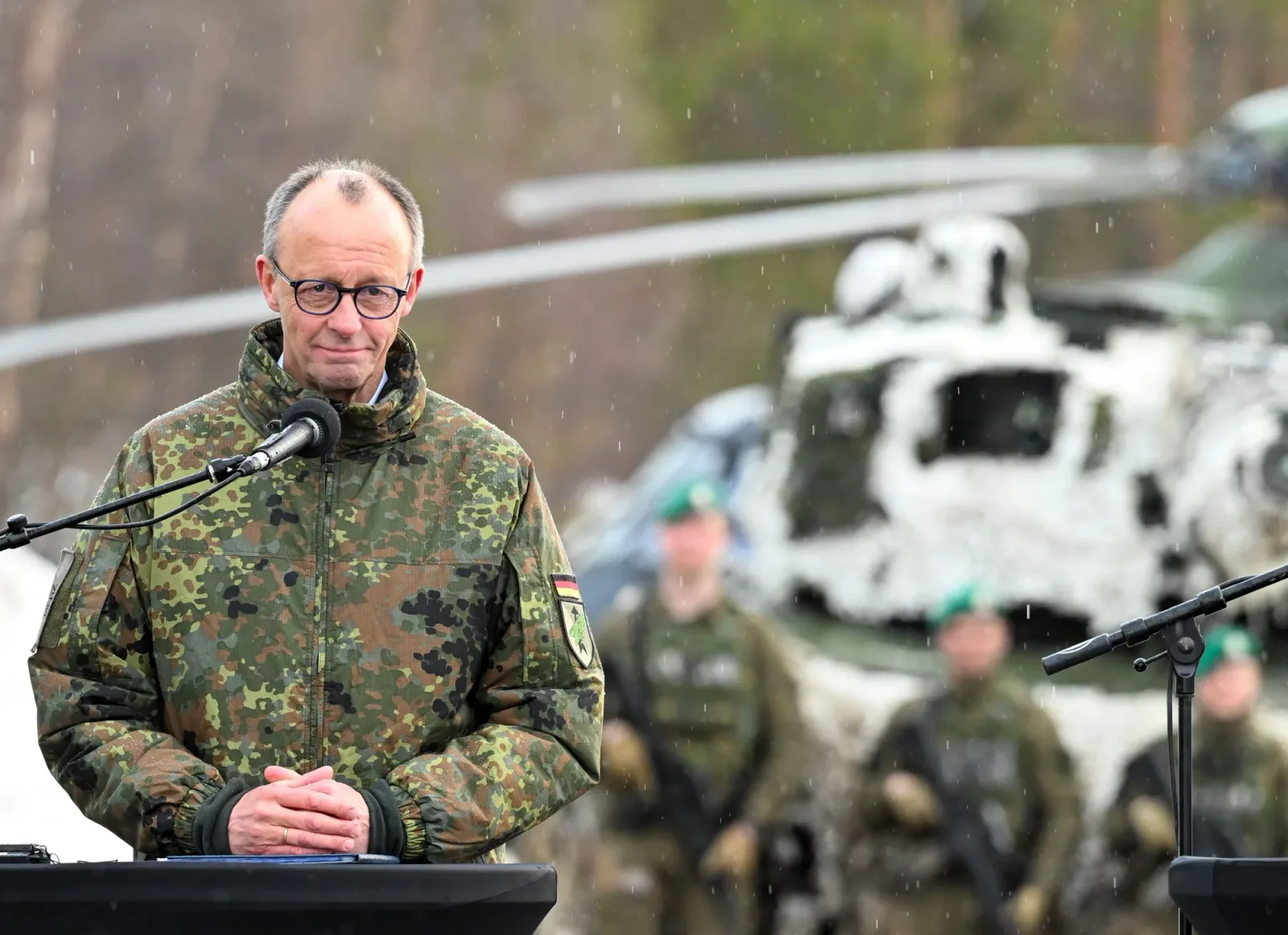 Friedrich Merz la o ceremonie militară cu elicoptere în fundal.