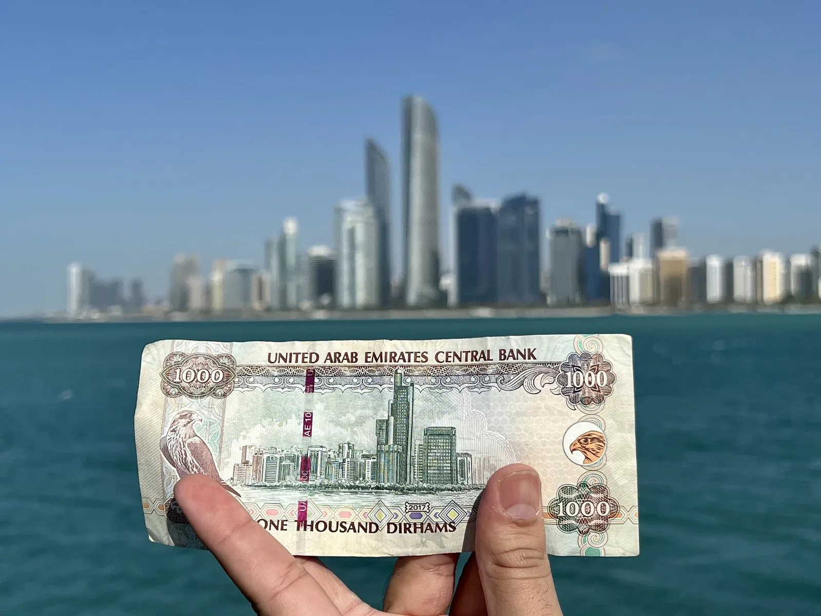 Bancnote de dirhami în fața unui peisaj urban modern din Emiratele Arabe Unite.