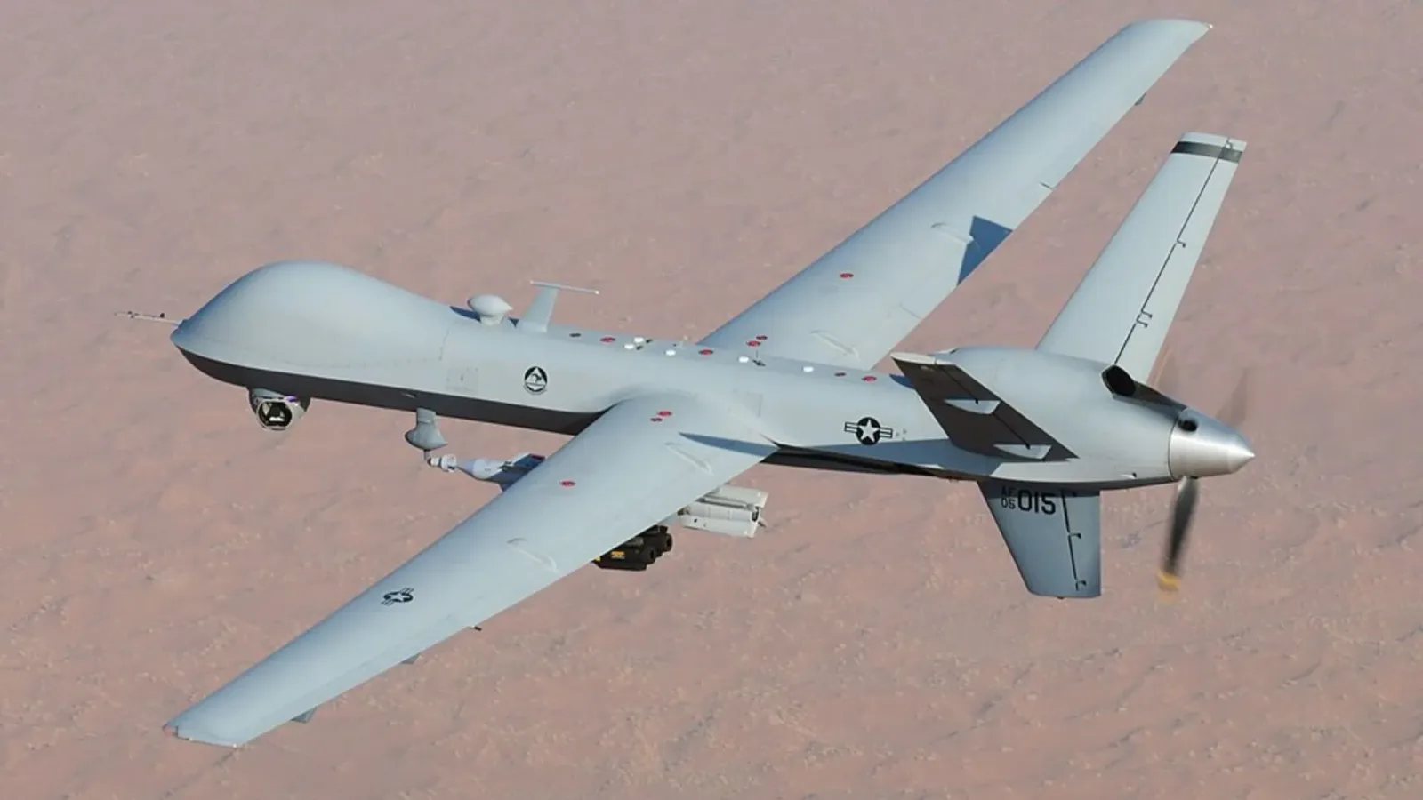 MQ-9 Reaper zburând deasupra unui peisaj arid, pregătit pentru misiuni complexe.