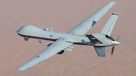 MQ-9 Reaper zburând deasupra unui peisaj arid, pregătit pentru misiuni complexe.