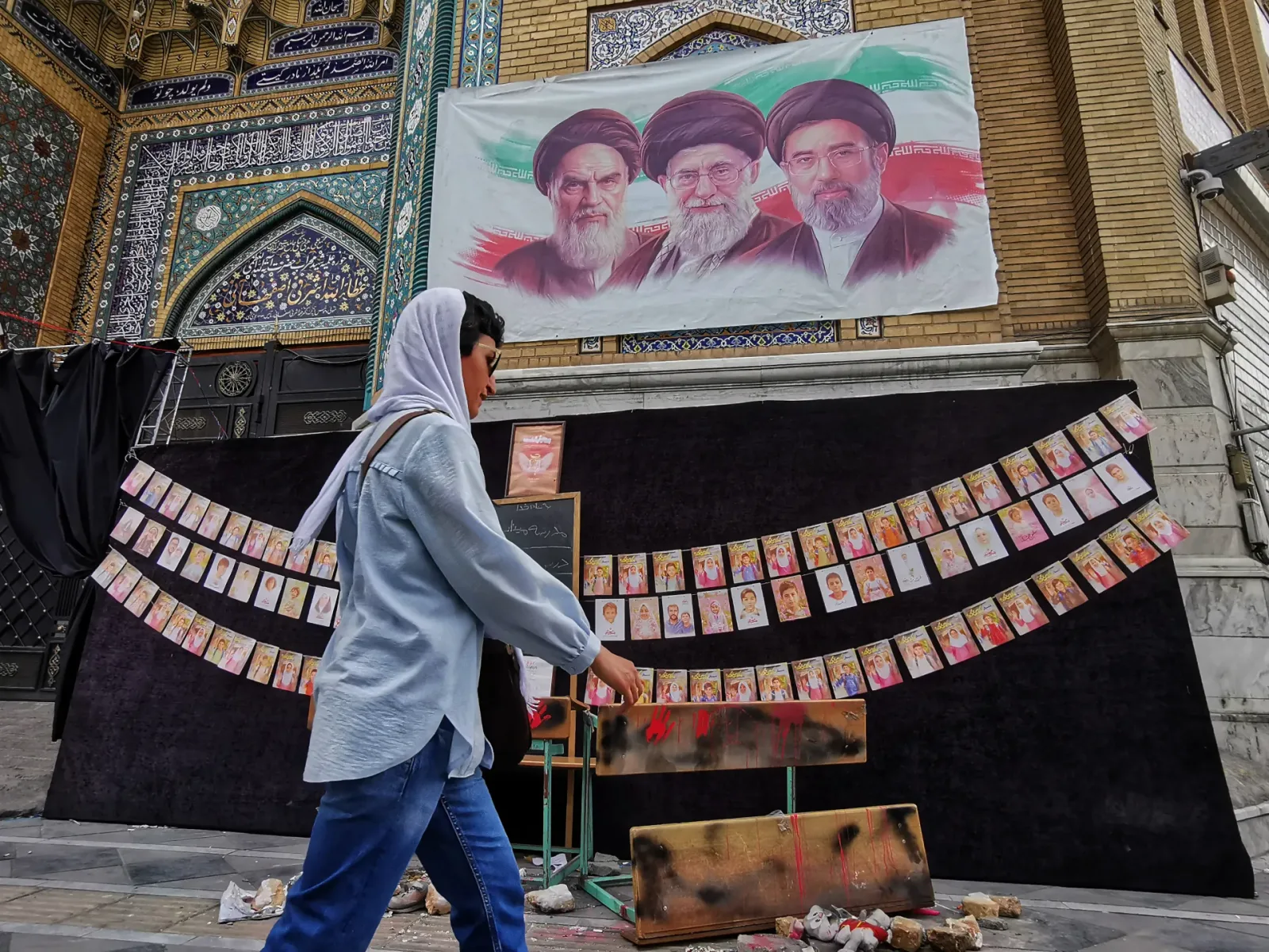 O persoană trece pe lângă un mural cu lideri iranieni în Teheran.