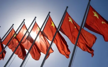 Steaguri roșii ale Chinei fluturând sub soare strălucitor.