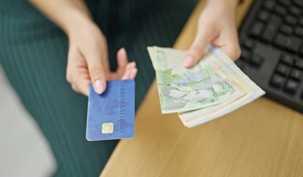 Persoană care ține o carte de credit și bancnote românești.
