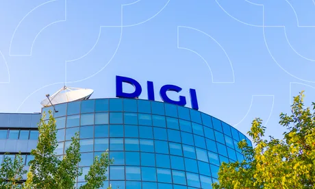 Clădirea Digi Communications sub un cer senin, cu vegetație în prim-plan.