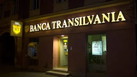 Sediul Băncii Transilvania iluminat noaptea, cu logo-ul vizibil.