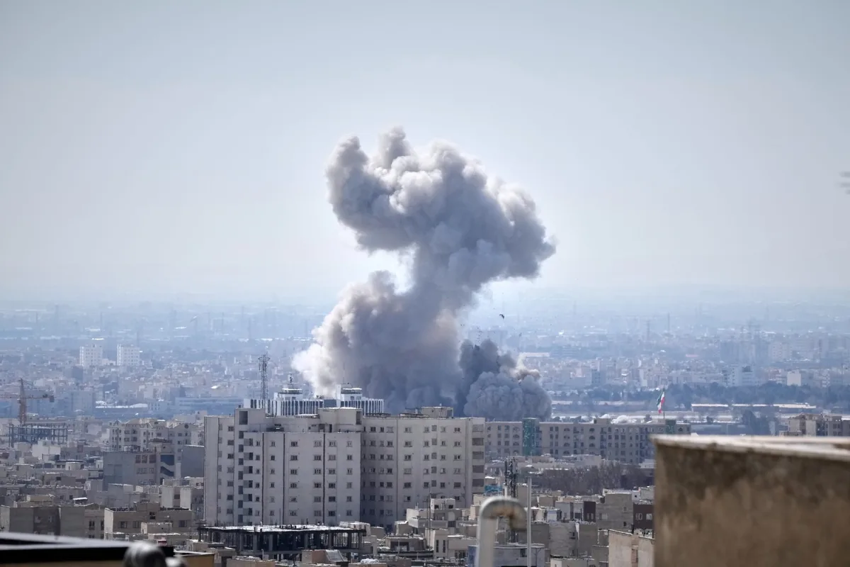 Fum gros ridicându-se deasupra orașului, semn al conflictului intens.