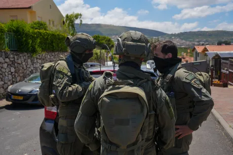 Soldați în echipament militar discutând pe o stradă dintr-o zonă montană.
