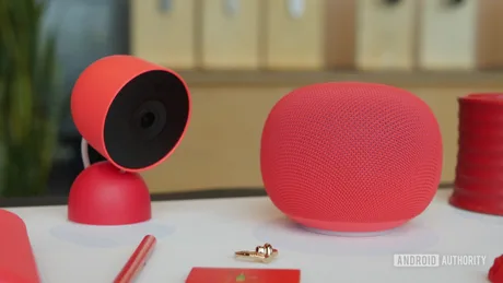 Dispozitive Google Home și Nest Cam în nuanțe roșii, pe o masă.