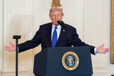 Donald Trump vorbește la microfon, gesticulând în fața publicului.