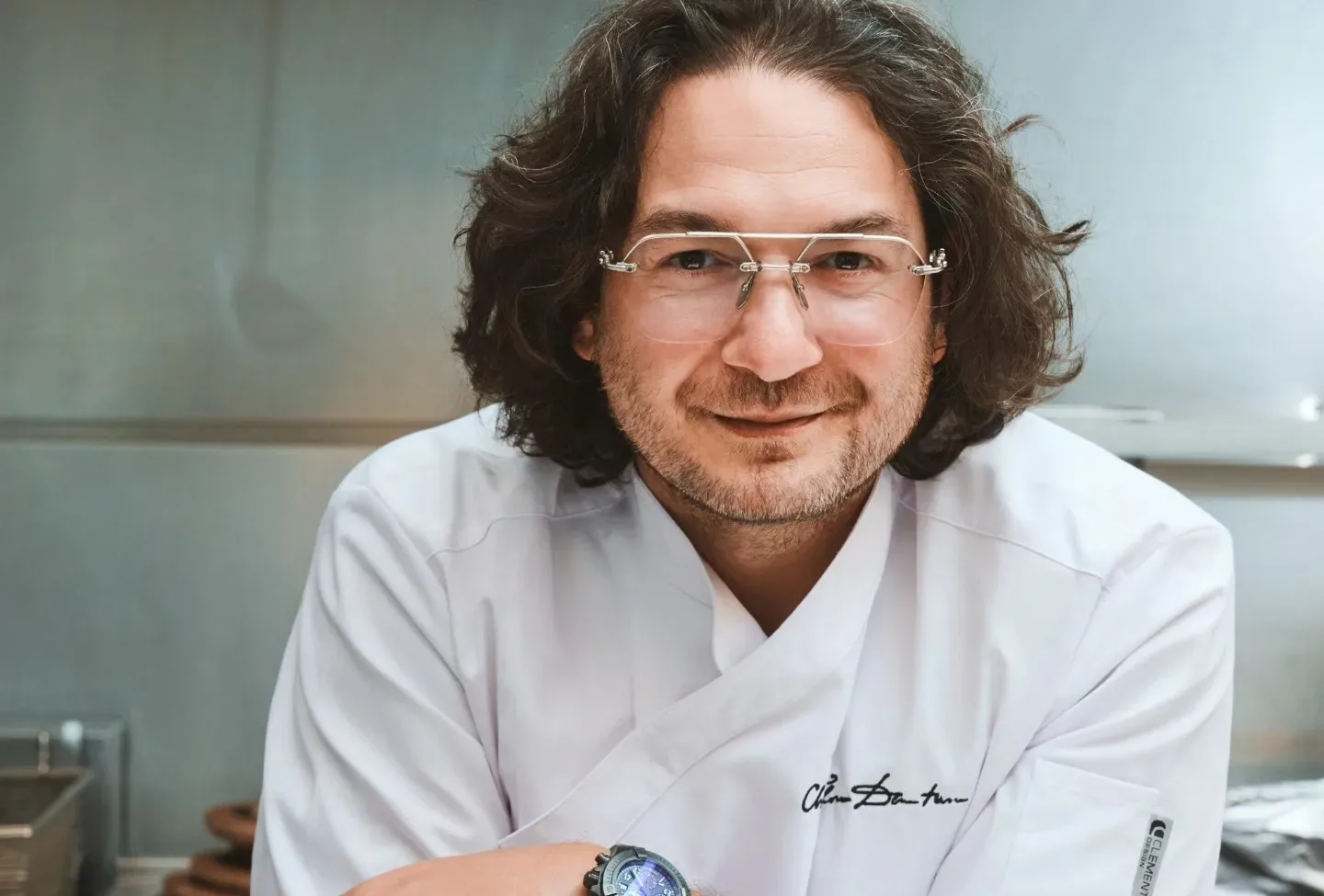 Florin Dumitrescu zâmbind în uniformă de bucătar, într-un mediu de gătit modern.