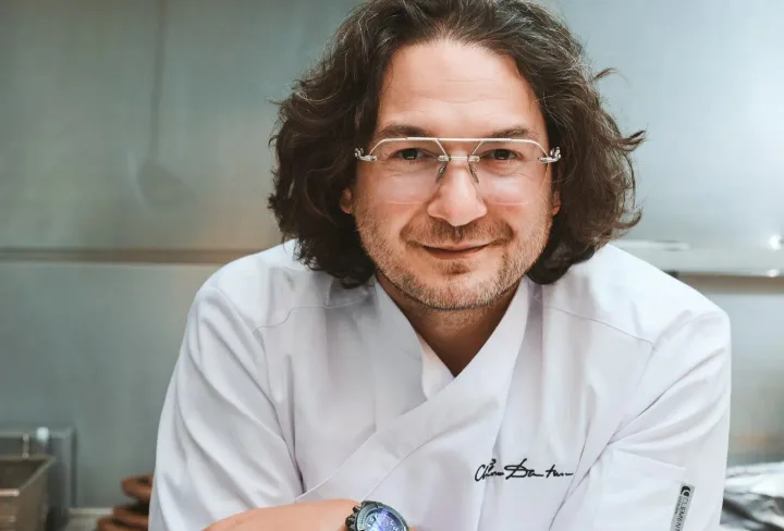 Florin Dumitrescu zâmbind în uniformă de bucătar, într-un mediu de gătit modern.
