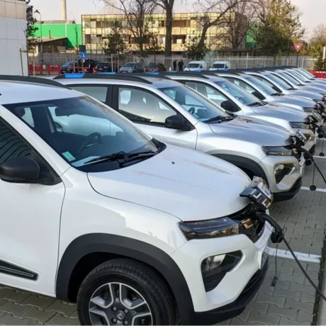 Mașini electrice parcate, pregătite pentru încărcare, într-o zonă urbană.