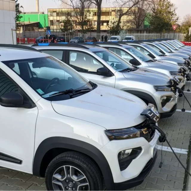 Mașini electrice parcate, pregătite pentru încărcare, într-o zonă urbană.