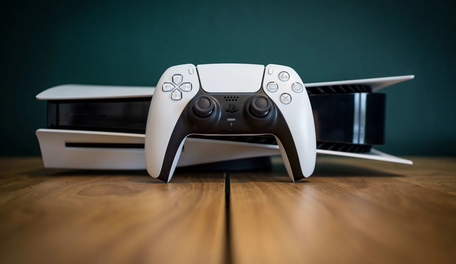 Controler PlayStation 5 pe un birou din lemn, cu fundal verde.