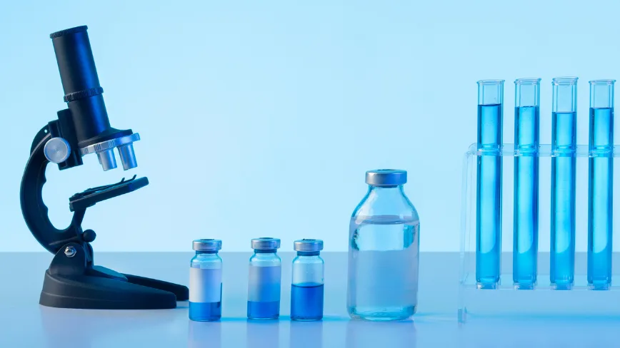 Microscop și eprubete cu soluții colorate pentru cercetări științifice.