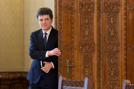Un oficial stând lângă o ușă ornamentată, într-un cadru elegant.