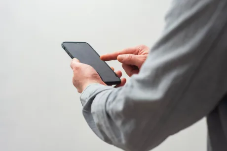 Utilizator care verifică telefonul mobil, posibil în context de roaming internațional.