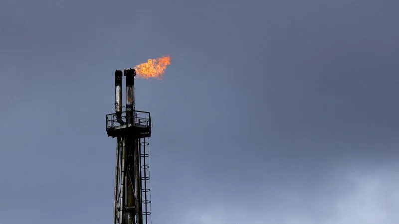 Flacără de gaz pe un turn de extracție petrolier în condiții de vreme închisă.