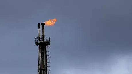 Flacără de gaz pe un turn de extracție petrolier în condiții de vreme închisă.