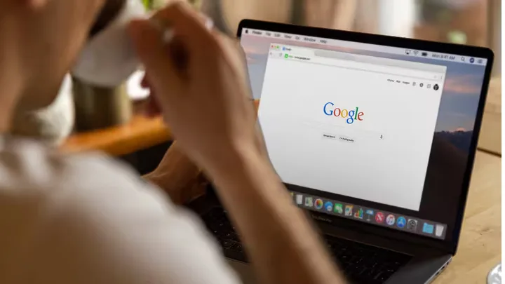 Utilizator navigând pe Google de pe un laptop.