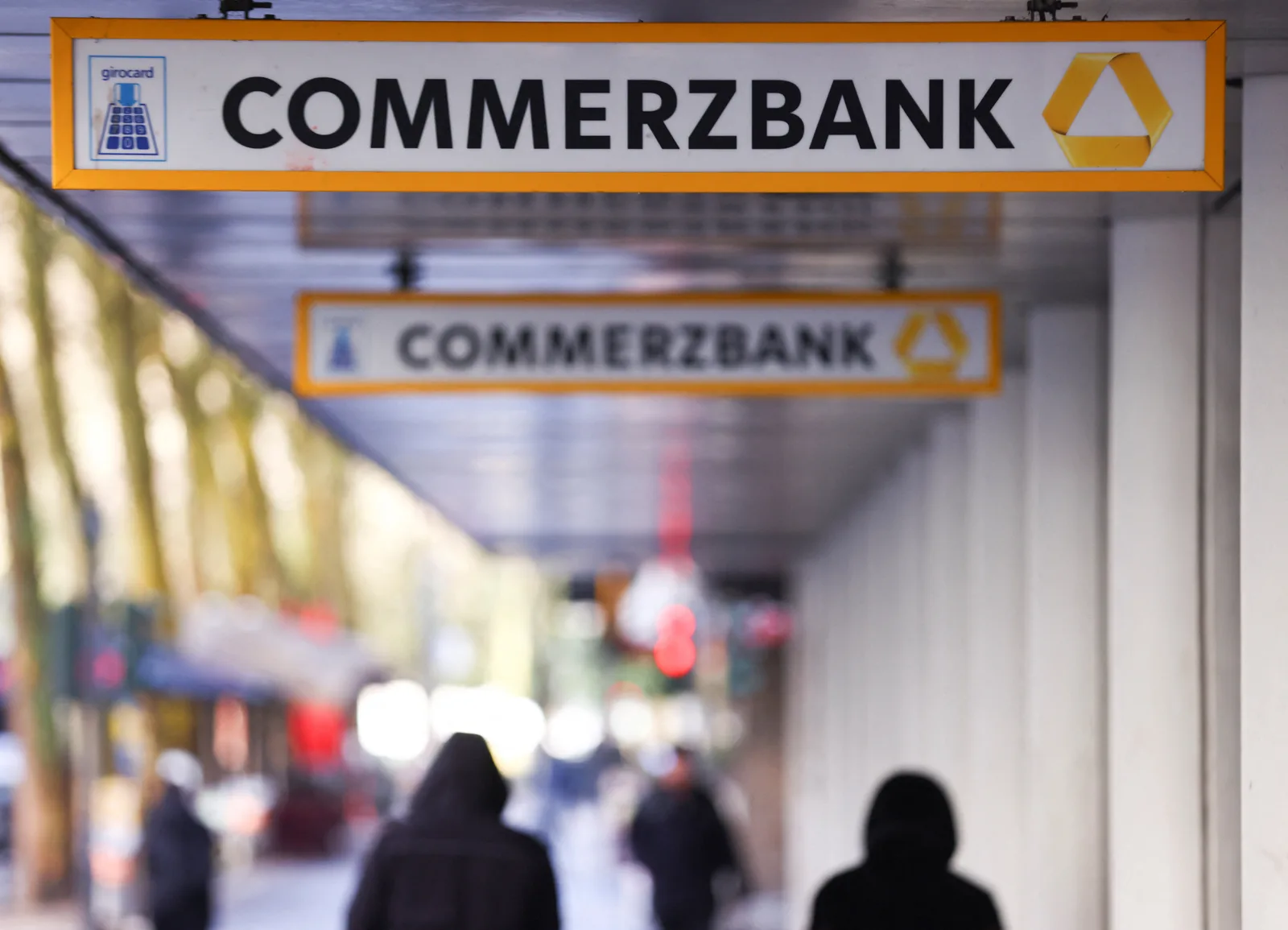 Sediul Commerzbank, cu oameni care trec pe lângă, simbolizând restructurarea bancară.